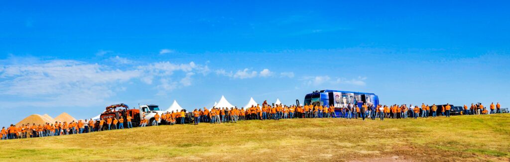 A panorama of Ditch Witch employees stand in a line at the top of a hill.